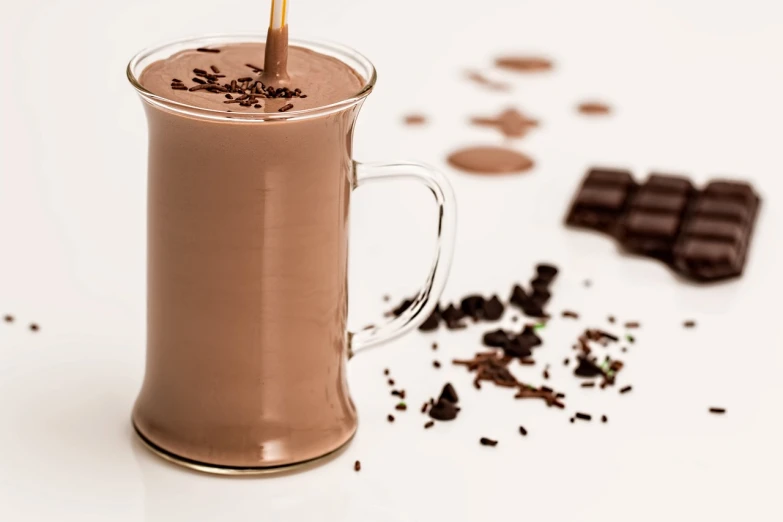 a glass of chocolate milk with a straw sticking out of it, by Franz Hegi, shutterstock, on a white table, detailed product photo, smothered in melted chocolate, recipe