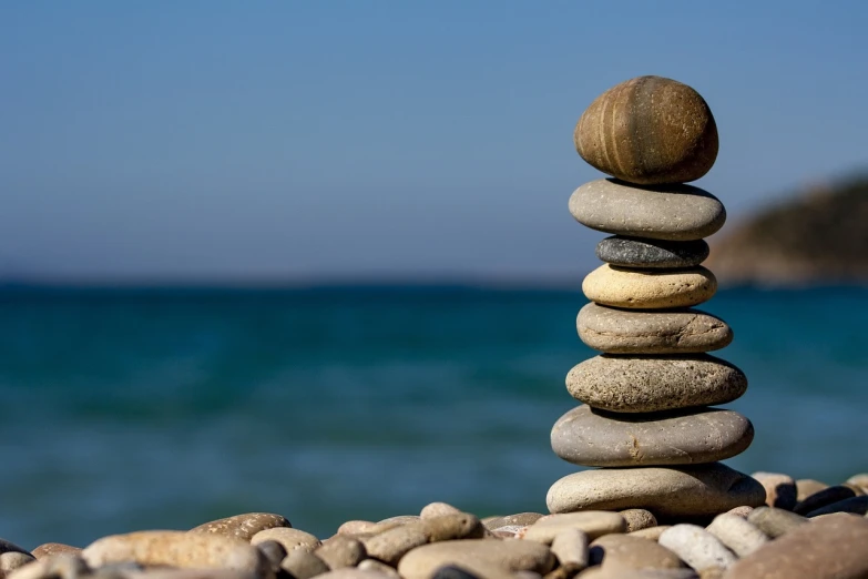 a stack of rocks sitting on top of a beach, a picture, smooth round rocks, stability at last, is relaxing on a beach, rock wall