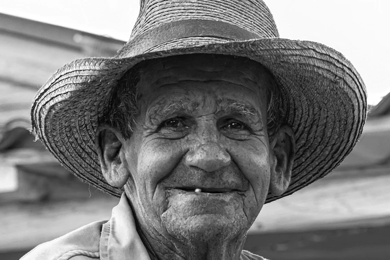 a black and white photo of a man wearing a hat, a black and white photo, inspired by Dorothea Lange, pixabay contest winner, photorealism, detailed smile, florida man, wearing straw hat, an 80 year old man