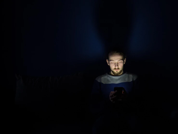 a man looking at his cell phone in the dark, by Adam Marczyński, watching tv, dark blue atmosphere, staring at the viewer, social media