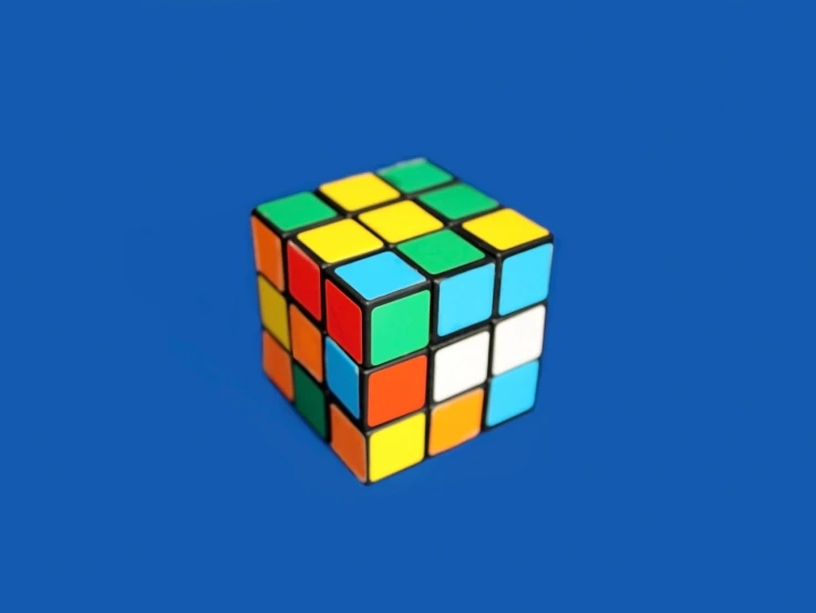 a rubik cube sitting on top of a blue surface, inspired by Ernő Rubik, 3d game object, brilliantly coloured, 3 2 years old, black 3 d cuboid device