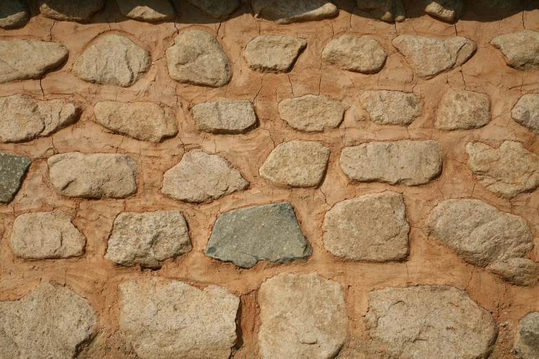 a red fire hydrant sitting in front of a stone wall, by Hans Fischer, mingei, texture of sand, trulli, street of teal stone, white stones