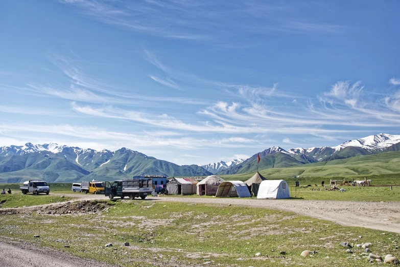 a group of vehicles parked on the side of a dirt road, by Muggur, flickr, tent camp in foreground, tourist destination, yuli ban, springtime