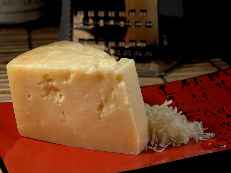 a piece of cheese sitting on top of a red plate, by Jan Rustem, shot with a arriflex 35 ii, pale ivory skin, side - view, highly detailed!