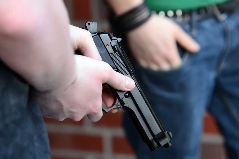 a close up of a person holding a gun, a photo, person in foreground, [ [ hyperrealistic ] ], high school, gripping