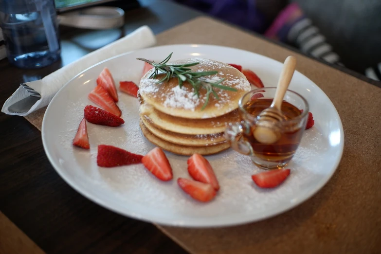 a white plate topped with pancakes and strawberries, renaissance, in tokio, 50mm photo, maple syrup sea, cafe