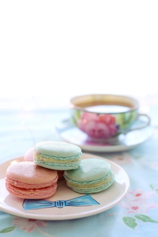 a white plate topped with macarons next to a cup of coffee, a pastel, by Shen Che-Tsai, tumblr, romanticism, blue and pink colors, shallow dof, colorful”