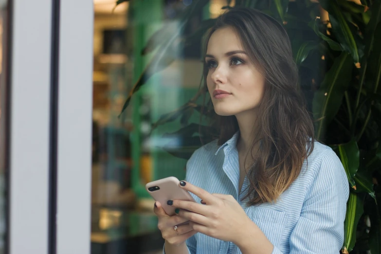 a woman is looking at her cell phone, by Emma Andijewska, pexels, realism, portrait of ana de armas, next to a big window, mobile learning app prototype, advertising