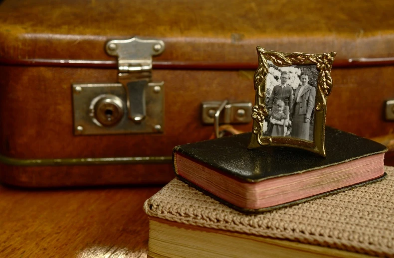 a picture frame sitting on top of a book, by Sylvia Wishart, flickr, in suitcase, family portrait, old timey, portrait of a small