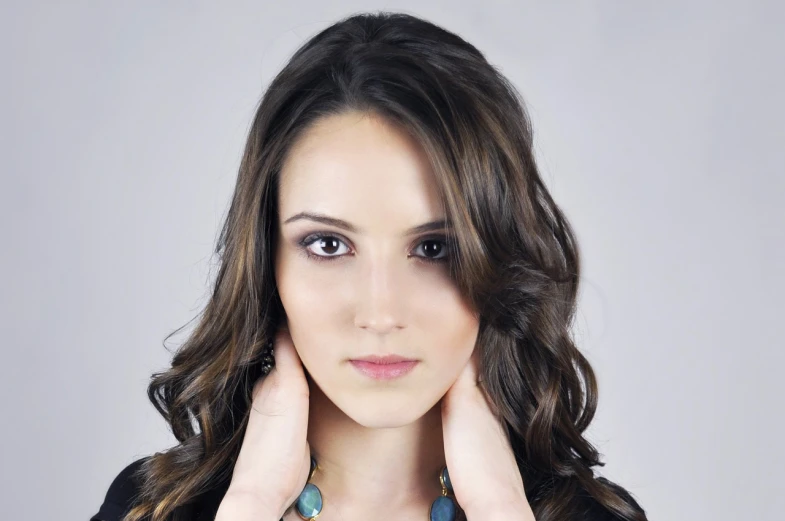 a close up of a person wearing a necklace, a digital rendering, realism, attractive female face!!!, photo from a promo shoot, long wavy brunette hair, stylized portrait h 1280