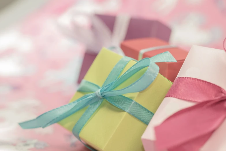 a pile of gift boxes sitting on top of a table, a picture, by Alice Mason, pixabay, green and pink colour palette, yellow and blue ribbons, closeup photo, pastel background