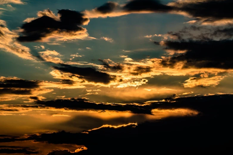 a plane flying through a cloudy sky at sunset, a picture, by Hans Schwarz, pexels, romanticism, dappled golden sunset, many golden layers, sunrays between clouds, blackened clouds cover sky
