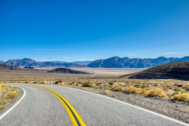 a road in the middle of a desert with mountains in the background, a picture, by Jeffrey Smith, shutterstock, wide angle shot 4 k hdr, on a bright day, panoramic photography, california;