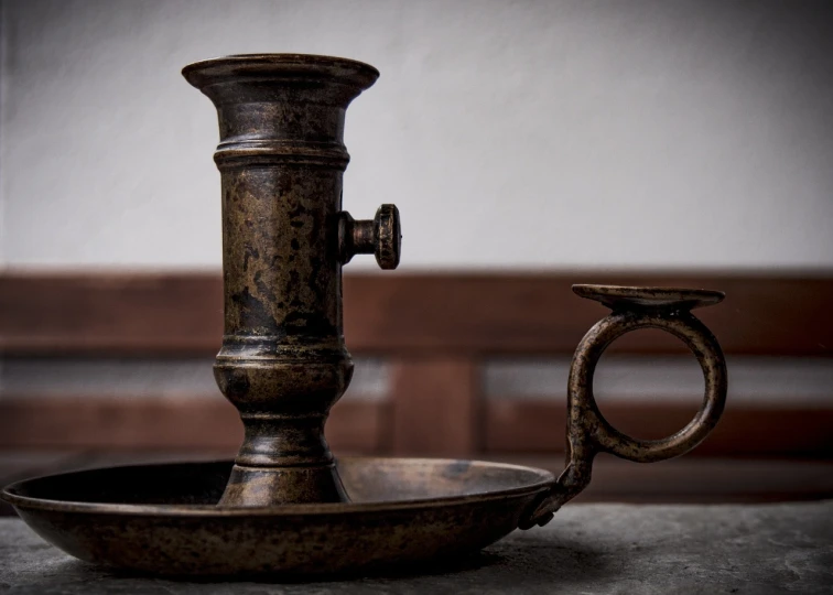 a metal candle holder sitting on top of a table, a still life, by Frederik Vermehren, unsplash, baroque, grungy, pestle, profile picture 1024px, half image