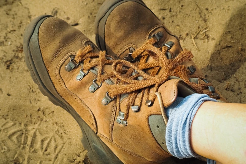 a pair of brown shoes sitting on top of a sandy ground, a portrait, shutterstock, trecking, close-up on legs, 3 4 5 3 1, protective