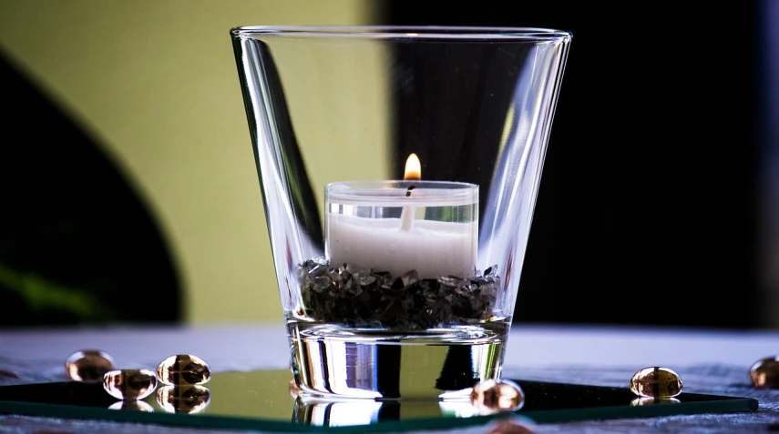 a candle that is sitting in a glass, by Jan Rustem, ashes crystal, centerpiece, with clear glass, waist up