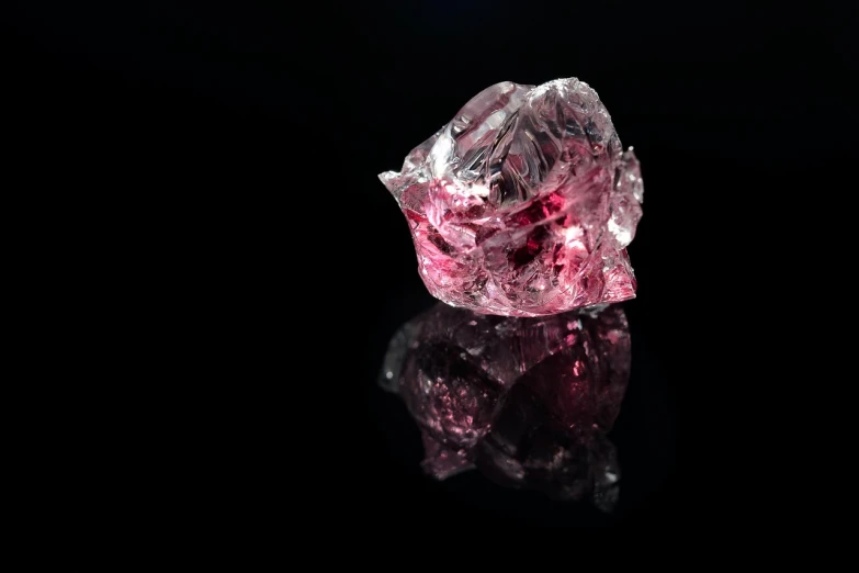 a pink diamond sitting on top of a black surface, by Julian Allen, pexels, glass antikythera, red beryl, in profile, icy