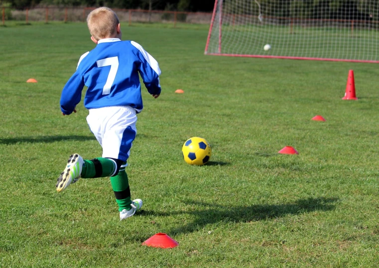 a young boy kicking a soccer ball on a field, dribble, cups and balls, file photo, cone heads, panels