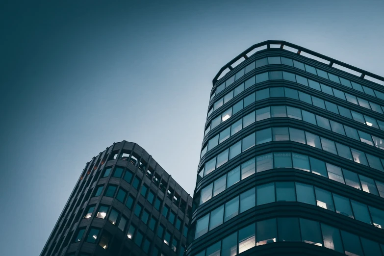 a couple of tall buildings next to each other, a stock photo, by Matthias Weischer, shutterstock, bauhaus, blue toned, rounded architecture, taken with sigma 2 0 mm f 1. 4, low-key