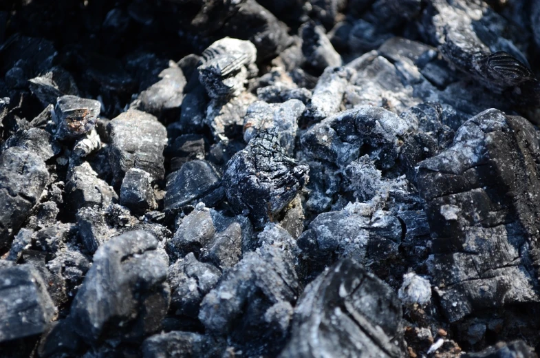 a pile of coal sitting on top of a pile of rocks, a portrait, pixabay, auto-destructive art, smouldering charred timber, hedi slimane, we didn't start the fire, warm sunshine