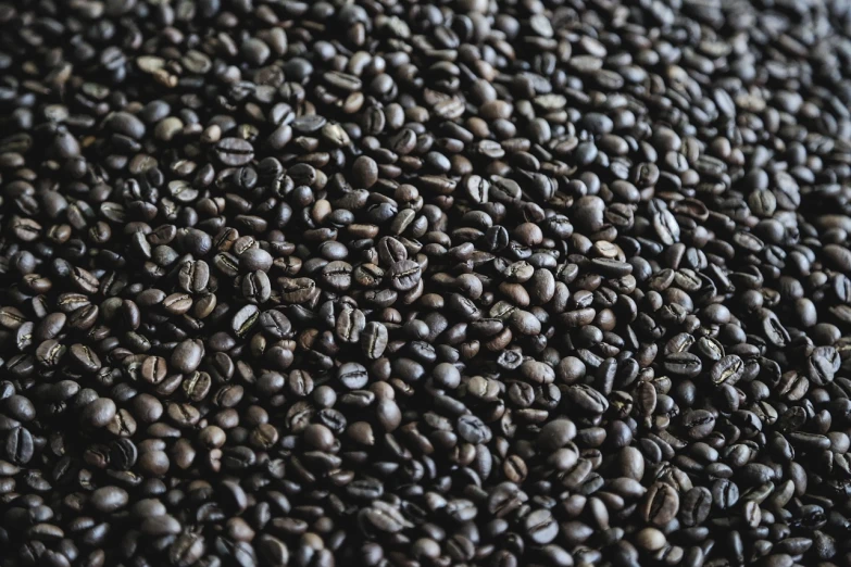 a pile of coffee beans sitting on top of a table, a macro photograph, pexels, background image, 4k high res, black textured, beautiful sunny day