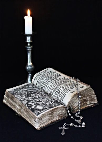 an open book sitting on top of a table next to a candle, an engraving, inspired by Abraham Hondius, pixabay, vanitas, ornate medieval religious icon, with ornate jewelled, high res photo, grisaille