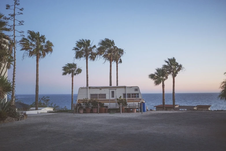 an rv parked in a parking lot next to the ocean, unsplash, palmtrees, usa-sep 20, early evening, desolate