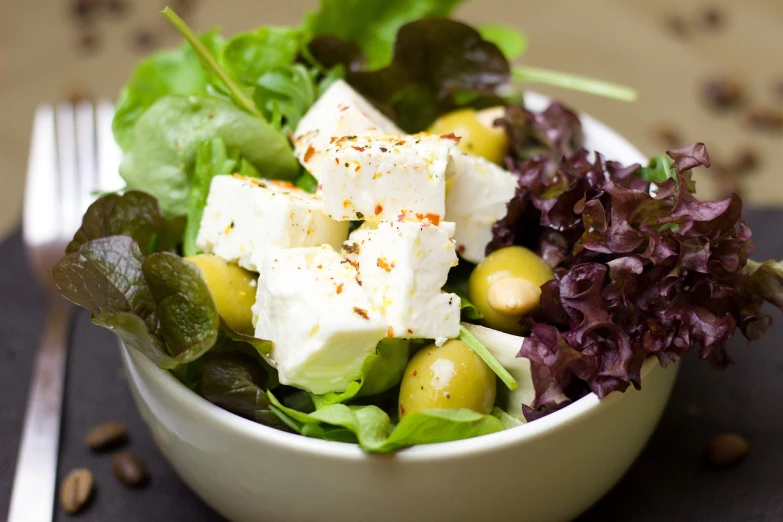 a close up of a bowl of food on a table, a picture, by Mathias Kollros, shutterstock, square, salad, (cheese), olives