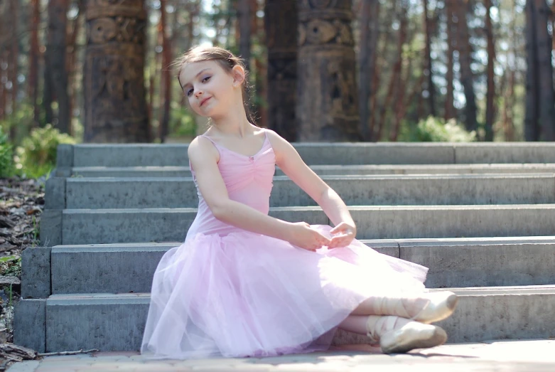 a little girl in a pink dress sitting on some steps, arabesque, dasha taran, peaceful and graceful, outside, smiling and dancing