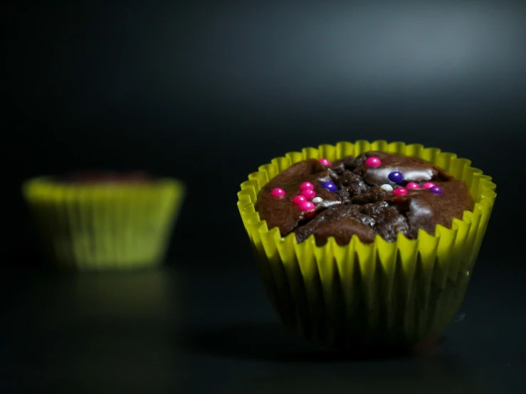 a chocolate cupcake with chocolate frosting and sprinkles, a portrait, pexels, minimalism, neon and dark, 4 k product photo, black and yellow colors, cinematic depth of field