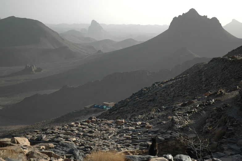 a group of people standing on top of a mountain, a detailed matte painting, flickr, les nabis, oman, tent camp in foreground, with lots of dark grey rocks, photo from the dig site