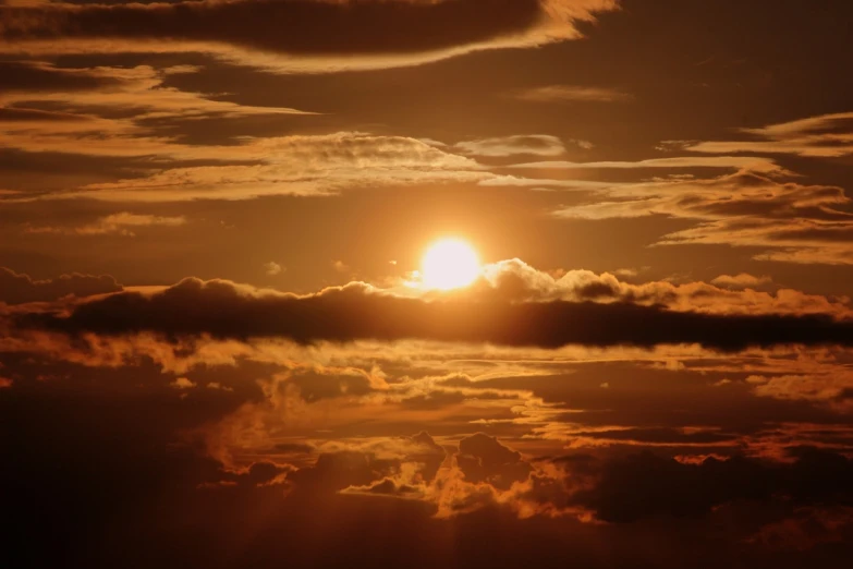 the sun is setting over the clouds in the sky, a picture, by Linda Sutton, pexels, romanticism, sepia sun, golden hues, hot sun from above, amber glow