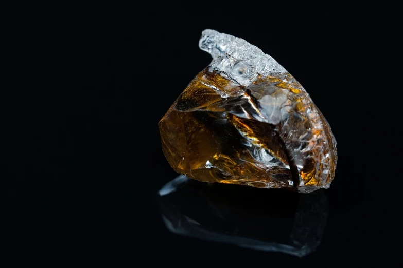 a close up of a diamond on a black surface, by Julian Allen, liquid translucent amber, chewing tobacco, enclosed in rock, 1/4 profile