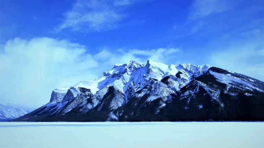 a man riding a horse across a snow covered field, a matte painting, inspired by James Pittendrigh MacGillivray, pexels, bakelite rocky mountains, lake blue, winter photograph, pure blue sky