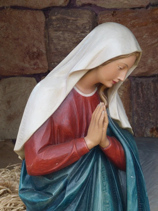 a statue of a woman praying in front of a stone wall, a statue, inspired by Mary Cameron, shutterstock, fine art, christmas, catholic icon, beautifully painted, 3/4 view realistic