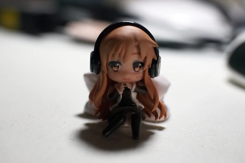 a close up of a doll with headphones on, inspired by Niko Henrichon, pixiv, figuration libre, mini figure, asuna yuuki, noire photo, in a chill position