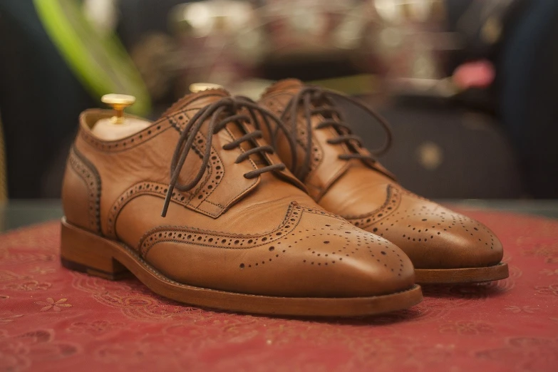 a pair of brown shoes sitting on top of a table, hurufiyya, professional product photography, finely detailed features, hand made, style of anton fadeev