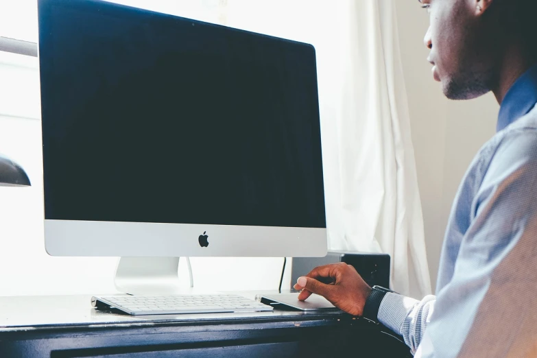 a man sitting at a desk in front of a computer, pexels, with apple, high res photo, 33mm photo, set photo