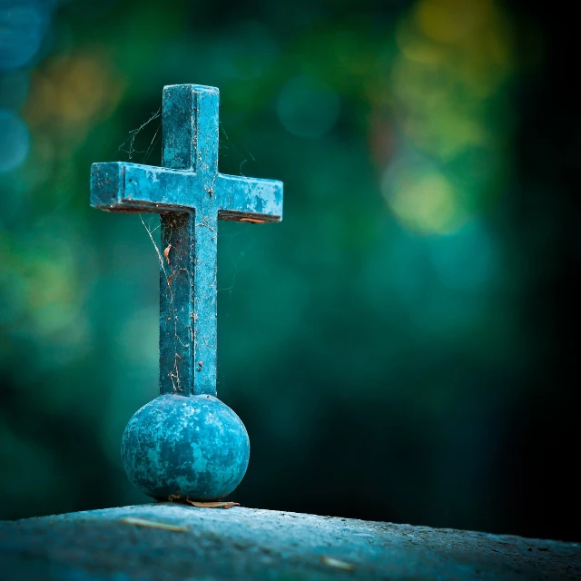 a blue cross sitting on top of a stone, a tilt shift photo, verdigris, gothic background, focus on the object, orb