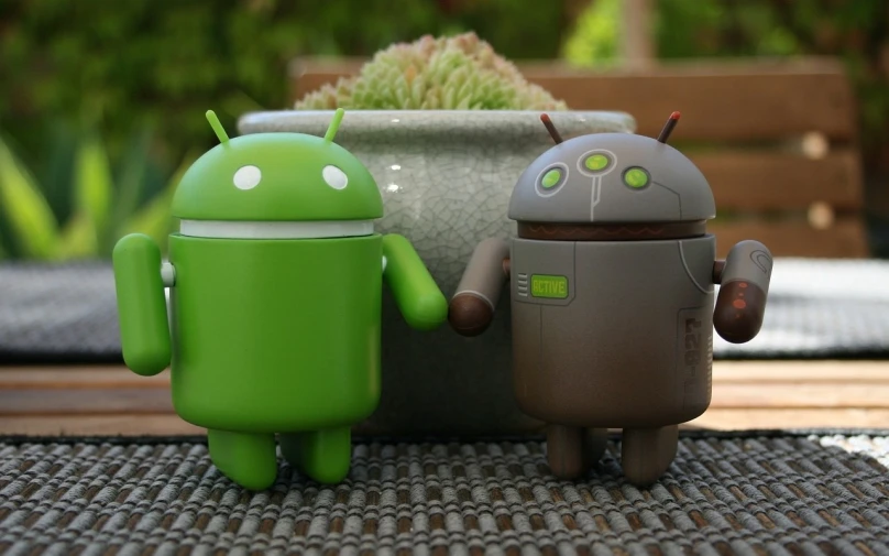 a couple of toy robots sitting next to each other, a picture, by Android Jones, green and warm theme, android phones, linux mint, candid shot