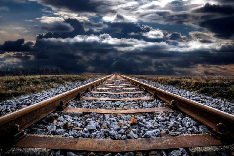 a train track surrounded by rocks under a cloudy sky, trending on pixabay, surrealism, stormy clouds on the horizon, upward shot, mobile wallpaper, lined up horizontally