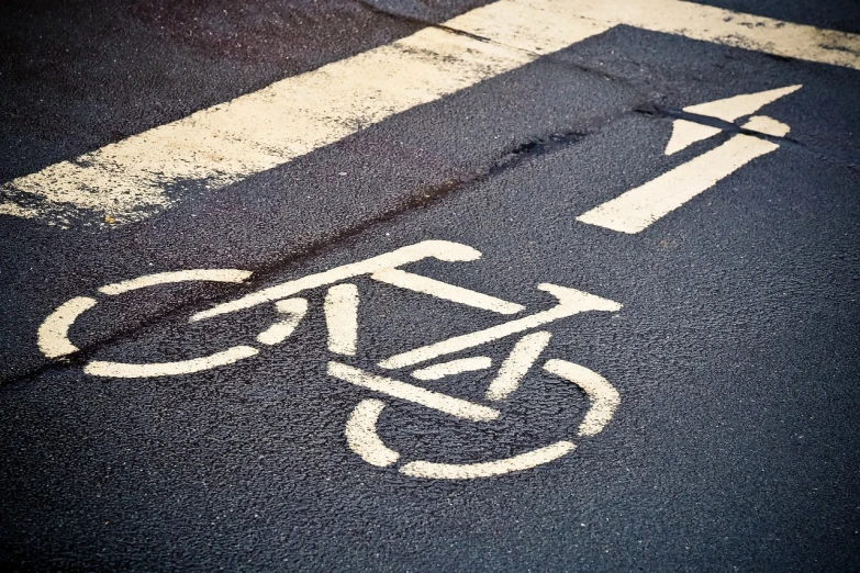 a bicycle is painted on the side of the road, by Richard Carline, flickr, grainy filter, traffic signs, high angle close up shot, high contrast!