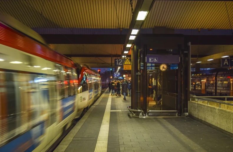 a train pulling into a train station next to a platform, by Jens Søndergaard, happening, busy night, stock photo