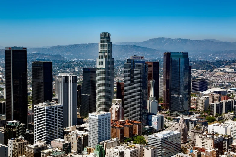 a view of a city with skyscrapers and mountains in the background, a stock photo, inspired by L. A. Ring, shutterstock, view from helicopter, southern california, shot with a canon 20mm lens, sunny day