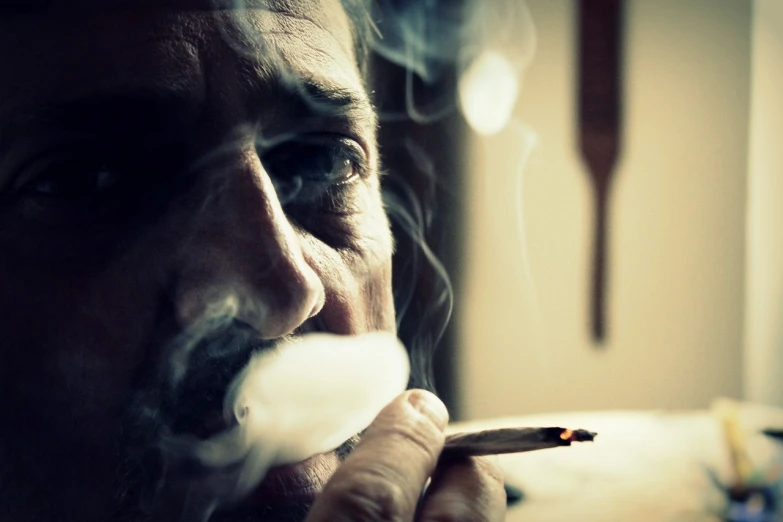 a close up of a person smoking a cigarette, a portrait, by Jesper Knudsen, unsplash, hyperrealism, ian mcshane, pot leaf, looking old, ray of light through smoke