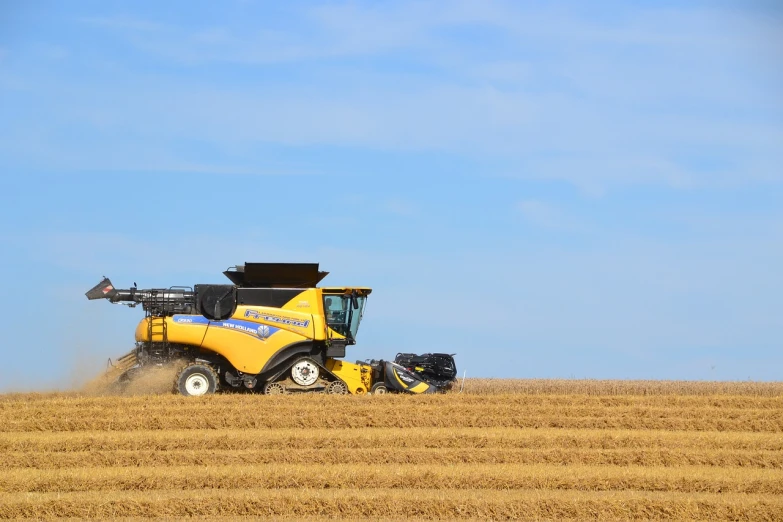 a tractor that is sitting in the middle of a field, a portrait, precisionism, yellow and blue, harvest, high grain, high quality product image”