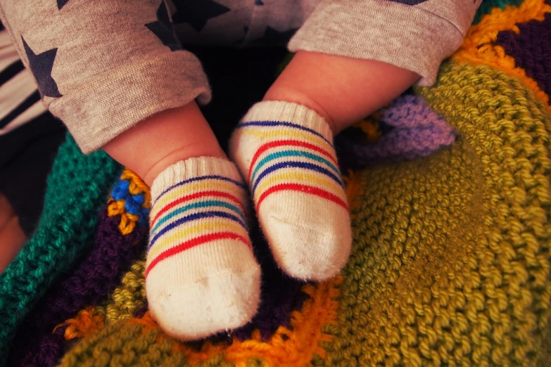 a close up of a child's feet wearing socks, inspired by Margaret Geddes, striped, ((oversaturated)), high res photo, cutie