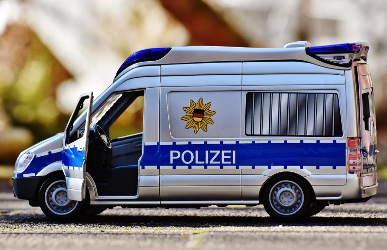 a toy police van parked on the side of the road, by Hans Schwarz, shutterstock, photorealism, german, detailed zoom photo, panorama, 🕹️ 😎 🔫 🤖 🚬