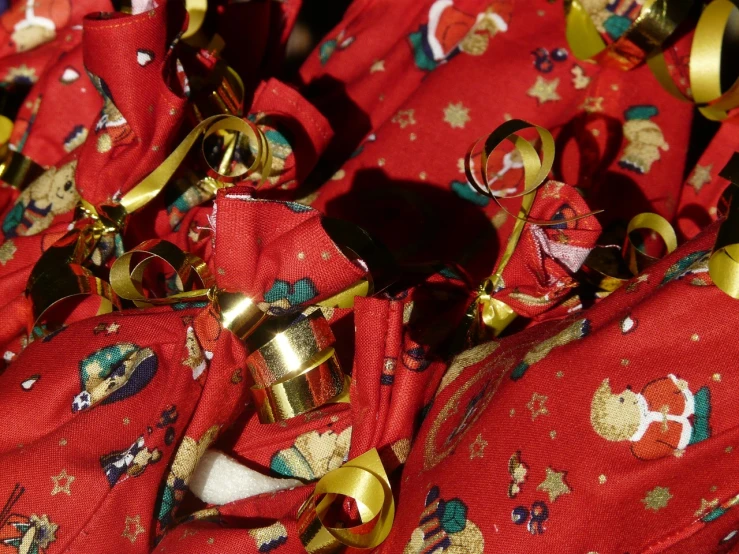 a bunch of bells sitting on top of a red bag, by Susan Heidi, pexels, process art, golden ribbons, close up face detail, cloth wraps, santa