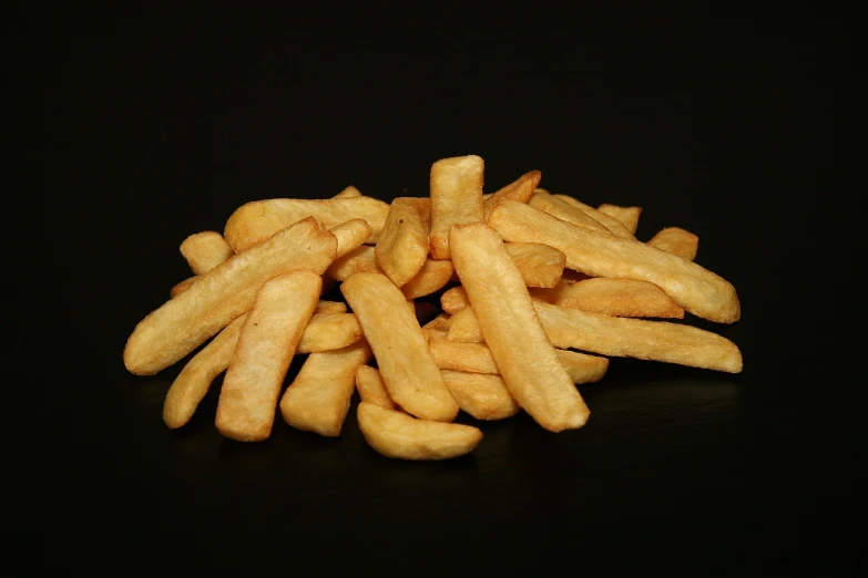 a pile of french fries sitting on top of a table, figuration libre, on black background, product introduction photo